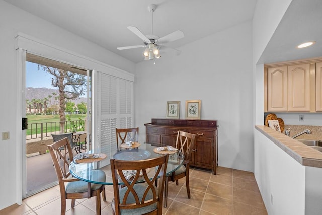 dining room with a mountain view, sink, light tile patterned floors, and ceiling fan