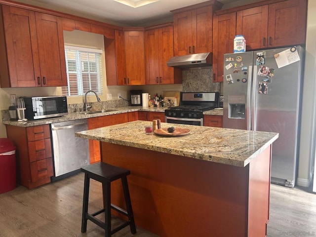 kitchen with a center island, appliances with stainless steel finishes, sink, and light wood-type flooring