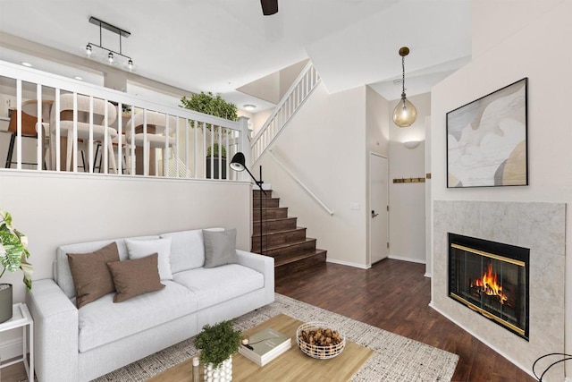 living room featuring a tiled fireplace, ceiling fan, and dark hardwood / wood-style flooring