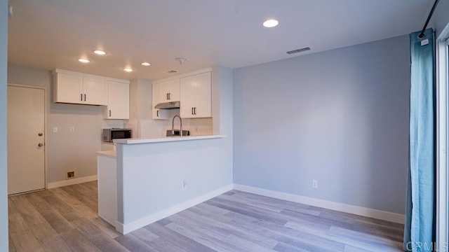 kitchen with white cabinetry, light hardwood / wood-style flooring, and kitchen peninsula