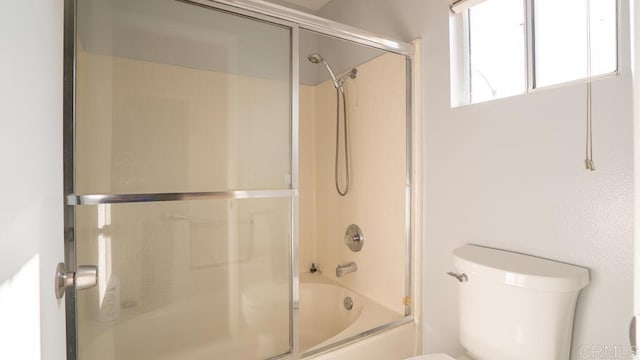 bathroom featuring bath / shower combo with glass door and toilet