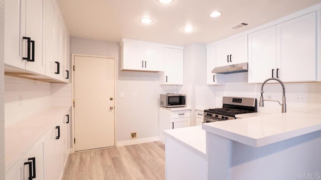 kitchen with white cabinetry, stainless steel appliances, kitchen peninsula, and light wood-type flooring