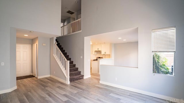 spare room with sink, light hardwood / wood-style flooring, and a high ceiling