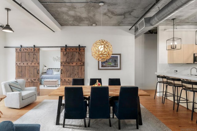 dining room featuring hardwood / wood-style flooring, a barn door, and a notable chandelier