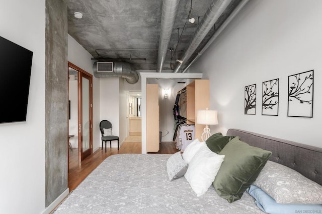 bedroom featuring wood-type flooring, a spacious closet, and a closet