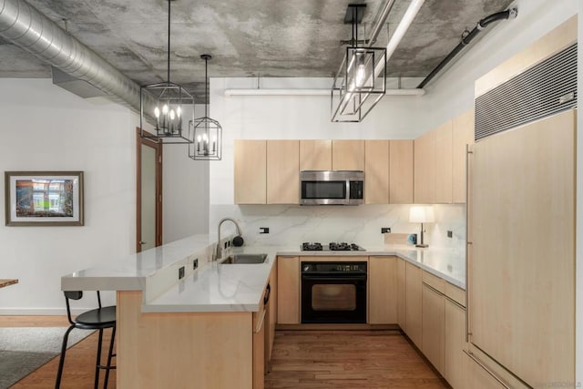 kitchen with sink, light brown cabinets, paneled refrigerator, kitchen peninsula, and oven