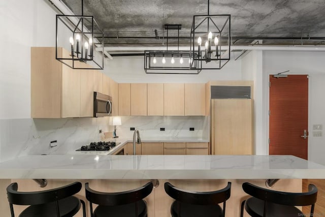 kitchen with kitchen peninsula, hanging light fixtures, and light brown cabinets