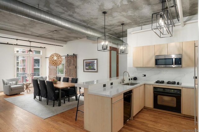 kitchen with sink, kitchen peninsula, light brown cabinetry, and black appliances