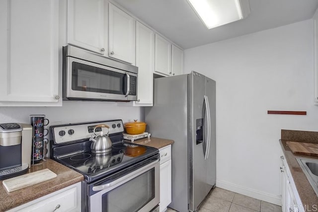 kitchen with dark countertops, white cabinetry, appliances with stainless steel finishes, and light tile patterned flooring