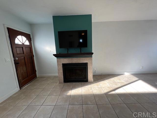 unfurnished living room with tile patterned flooring, a fireplace, and baseboards