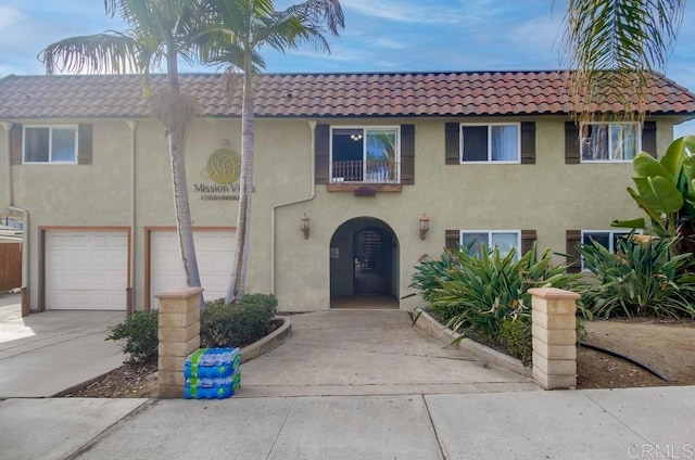 view of front of property with driveway, stucco siding, an attached garage, and a tiled roof