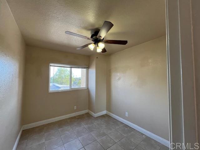 empty room featuring light tile patterned flooring, ceiling fan, a textured ceiling, and baseboards