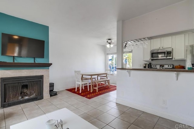 kitchen featuring light tile patterned floors, stove, white cabinetry, stainless steel microwave, and dark countertops