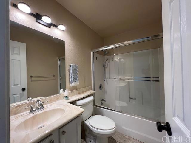 bathroom with tile patterned flooring, enclosed tub / shower combo, vanity, and toilet