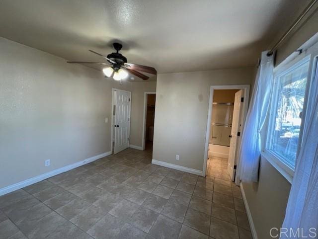 unfurnished bedroom with ceiling fan, connected bathroom, and baseboards