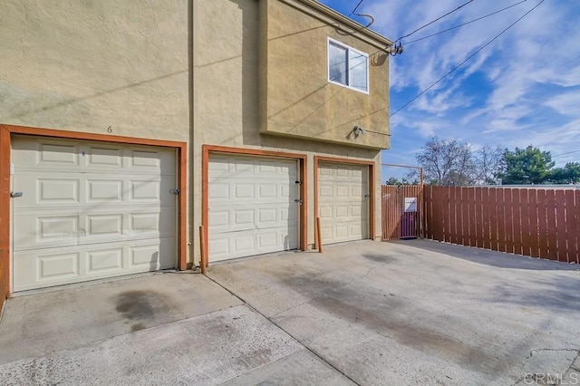 garage featuring fence and concrete driveway