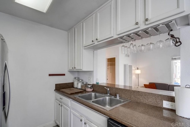 kitchen featuring dark countertops, white cabinets, a sink, dishwasher, and stainless steel fridge with ice dispenser