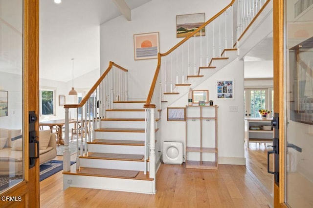 stairway featuring hardwood / wood-style floors and high vaulted ceiling