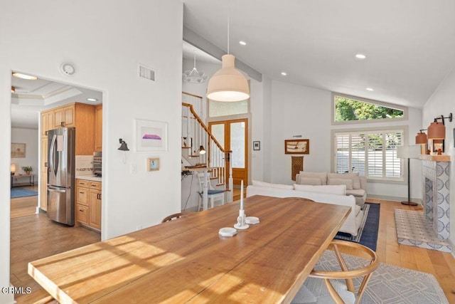 dining area with high vaulted ceiling and light hardwood / wood-style floors