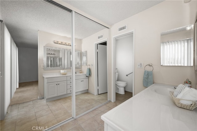 bathroom with tile patterned floors, vanity, toilet, and a textured ceiling