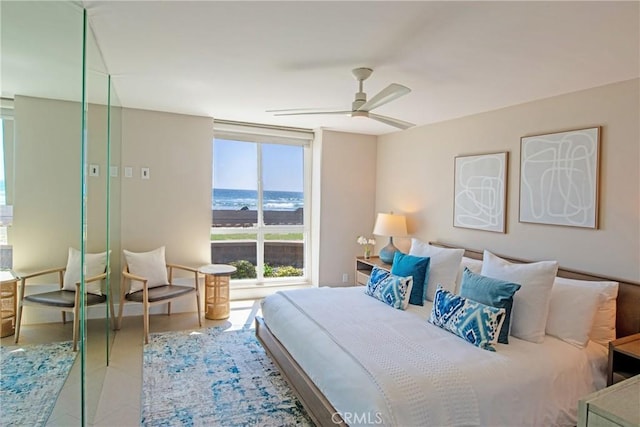 bedroom with a water view, light tile patterned floors, and ceiling fan