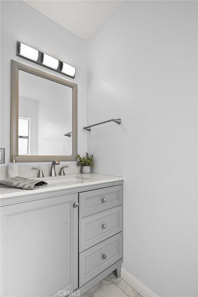 bathroom with marble finish floor, vanity, and baseboards