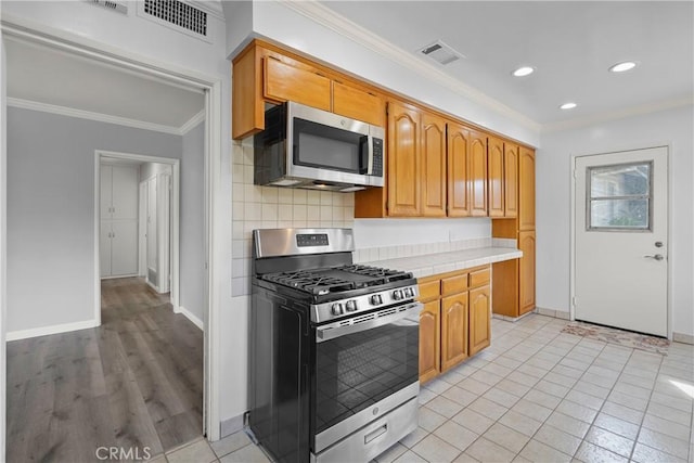 kitchen with visible vents, baseboards, ornamental molding, appliances with stainless steel finishes, and decorative backsplash