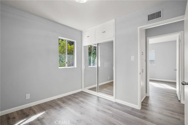 unfurnished bedroom featuring a closet, visible vents, light wood-style flooring, and baseboards