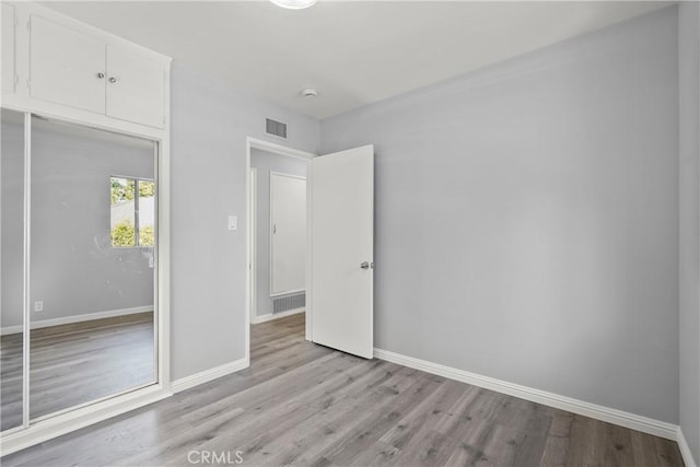 unfurnished bedroom with wood finished floors, visible vents, and baseboards