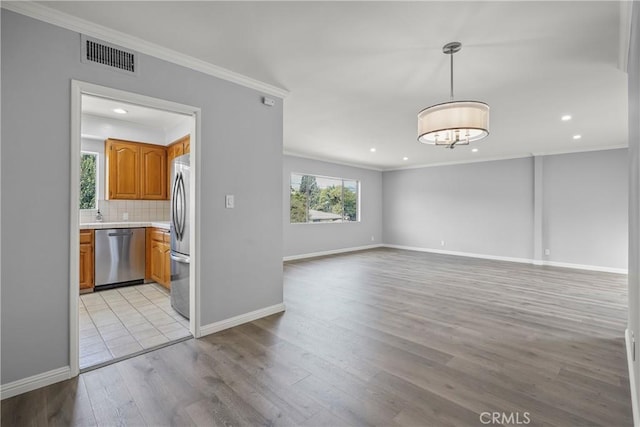 interior space with baseboards, light wood-type flooring, visible vents, and crown molding