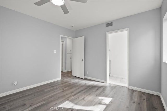 unfurnished bedroom featuring visible vents, baseboards, wood finished floors, and a ceiling fan