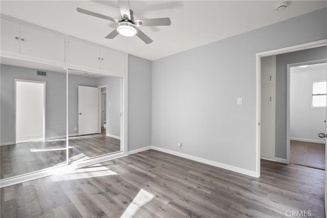 unfurnished bedroom with ceiling fan, wood finished floors, visible vents, and baseboards