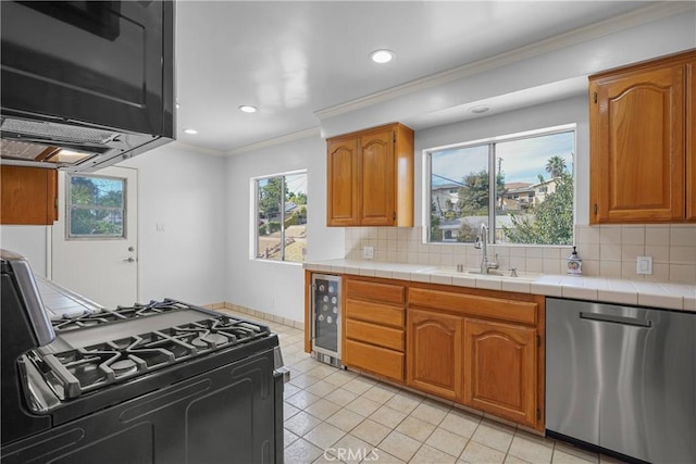 kitchen featuring tile counters, decorative backsplash, gas range, stainless steel dishwasher, and a sink