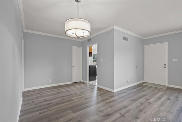 spare room featuring visible vents, baseboards, and wood finished floors