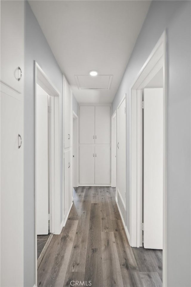 hallway featuring attic access and wood finished floors