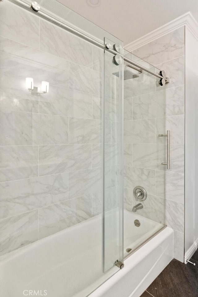 bathroom featuring combined bath / shower with glass door and crown molding