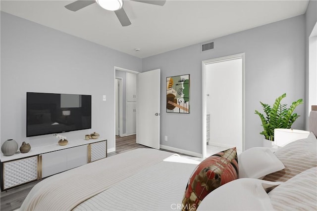 bedroom featuring a ceiling fan, wood finished floors, visible vents, and baseboards