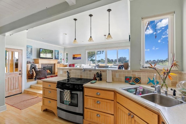 kitchen featuring a tiled fireplace, pendant lighting, stainless steel range with electric cooktop, and decorative backsplash