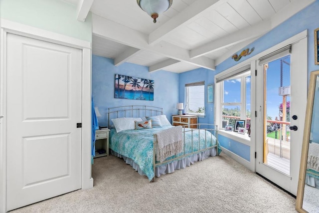 carpeted bedroom with beam ceiling and access to outside