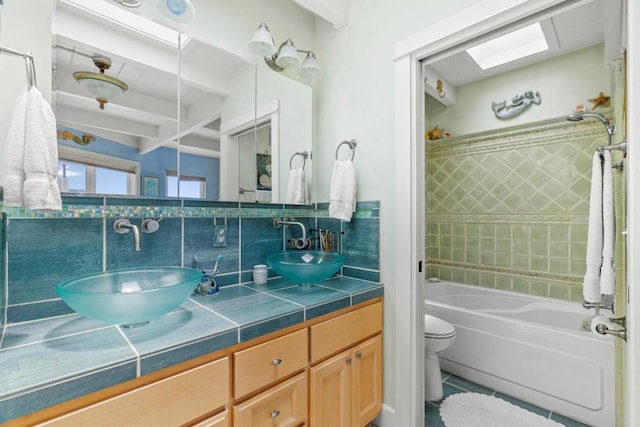 full bathroom with toilet, vanity, tiled shower / bath combo, tile patterned flooring, and decorative backsplash