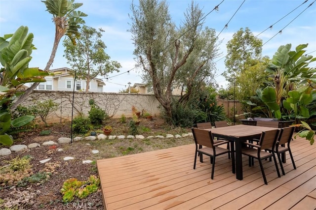 wooden terrace with outdoor dining space and a fenced backyard