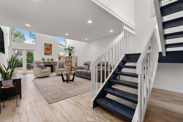 stairway with a brick fireplace, recessed lighting, wood finished floors, and french doors