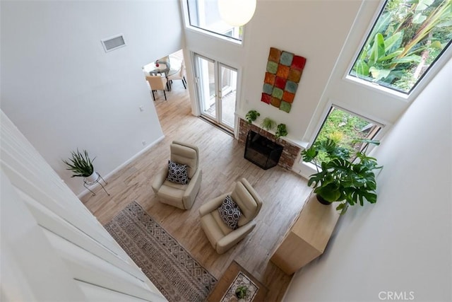 living area with light wood-type flooring, visible vents, a fireplace, and a towering ceiling