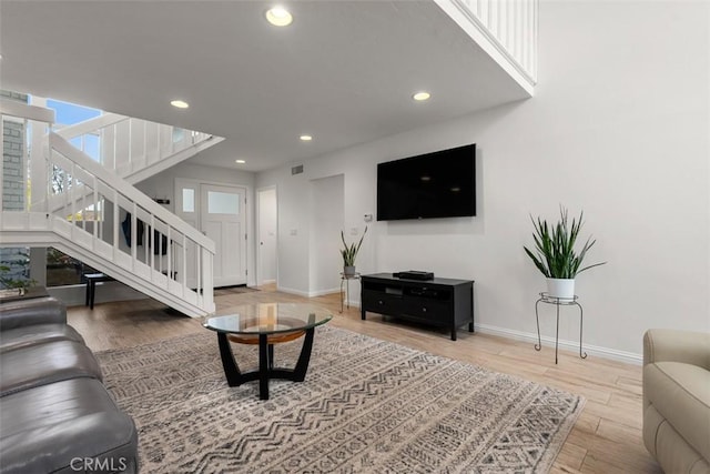 living room featuring stairway, baseboards, wood finished floors, and recessed lighting