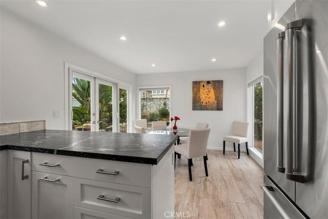 kitchen with high quality fridge, recessed lighting, light wood-style floors, french doors, and dark stone countertops