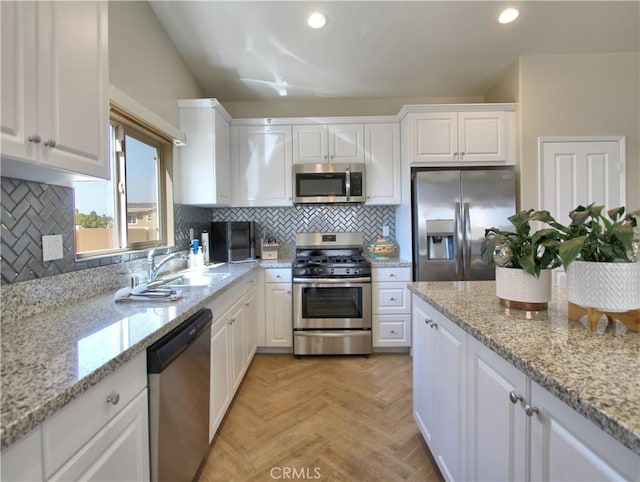 kitchen featuring stainless steel appliances, sink, light parquet flooring, light stone countertops, and white cabinets