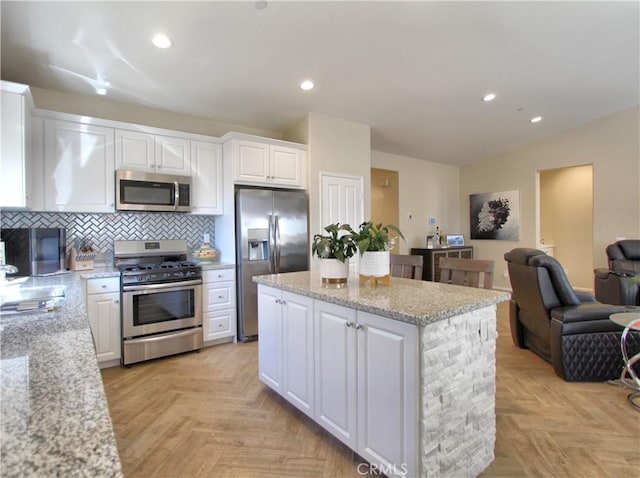 kitchen with light stone counters, appliances with stainless steel finishes, white cabinets, decorative backsplash, and light parquet floors