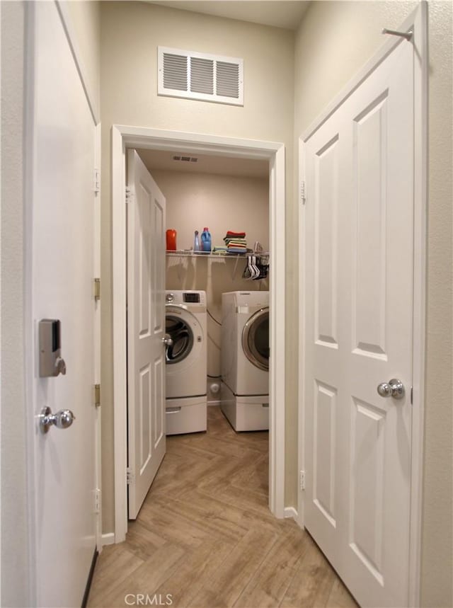 clothes washing area with independent washer and dryer and light parquet floors