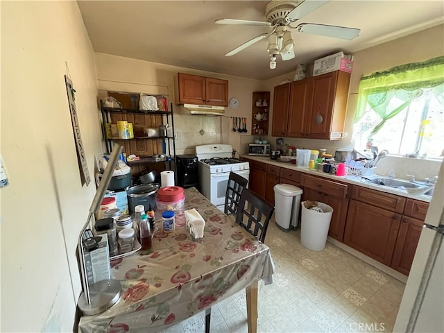 kitchen with tasteful backsplash, ceiling fan, sink, and white gas stove