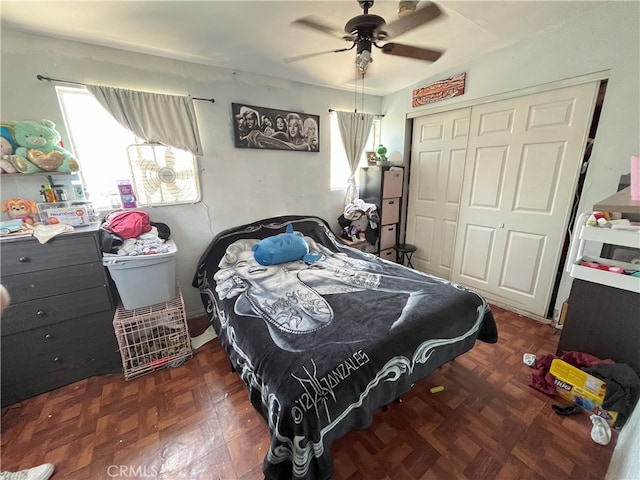 bedroom featuring ceiling fan, dark parquet flooring, and a closet